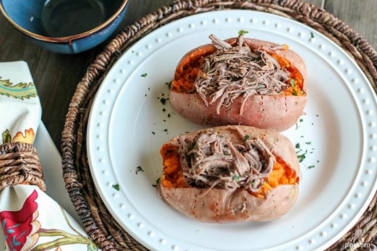 Shredded roast beef on sweet potatoes on white plate