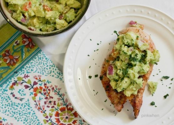 grilled chicken with avocado salsa on a white plate. 