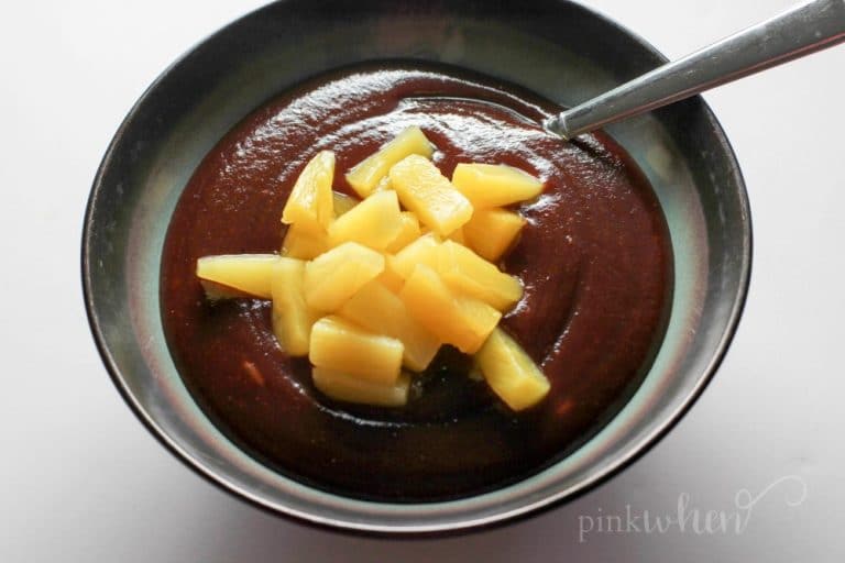 Pineapple on barbecue sauce in a bowl on a white table. 