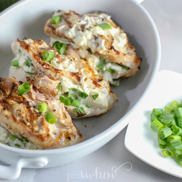 stuffed grilled chicken in a white serving dish. 