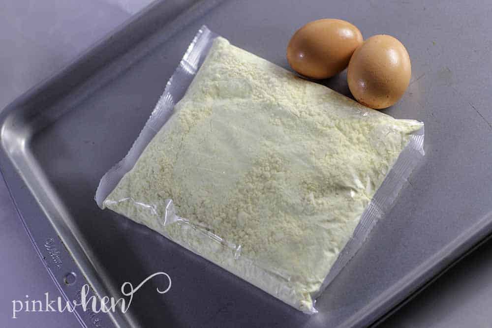 Cookie mix and eggs on a sheet pan in preparation to making Lemon Cake Mix Cookies. 