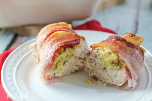 bacon wrapped stuffed chicken sliced open on a white plate.