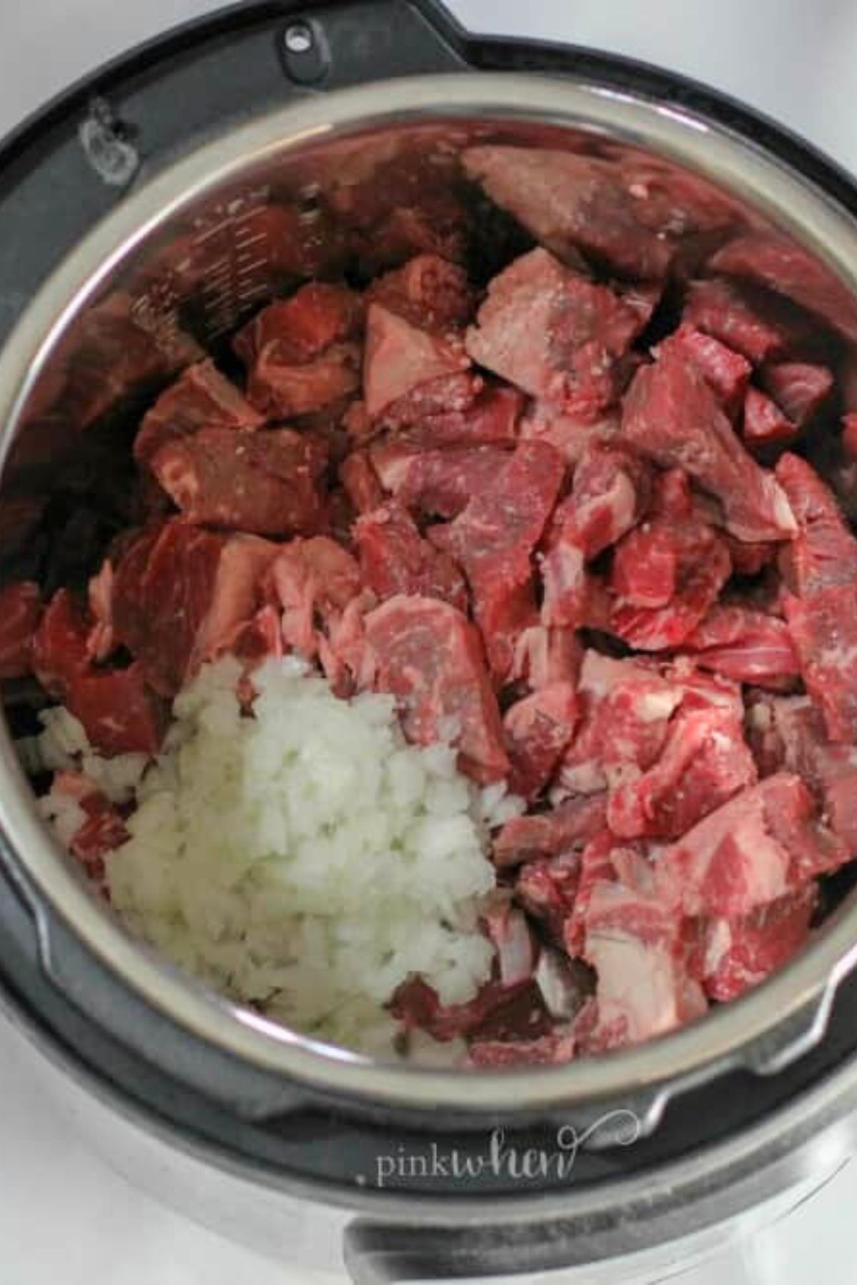Uncooked beef tips with other ingredients in the instant pot, before cooking.
