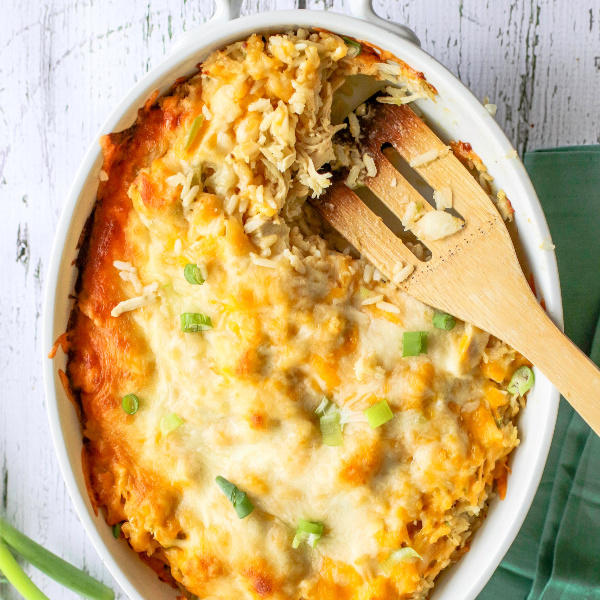 Chicken and Rice Casserole topped with cheese and garnishments on a white table. 