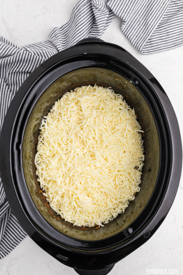 Cheese covering lasagna in a crockpot.