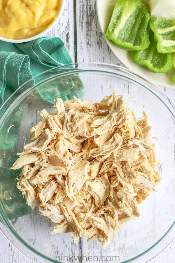 Shredded chicken in a glass bowl on a white table. 