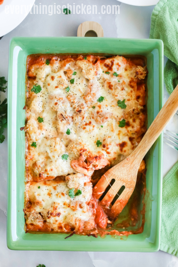Chicken Parmesan casserole that's been scooped and served and showing remainder in casserole dish. 