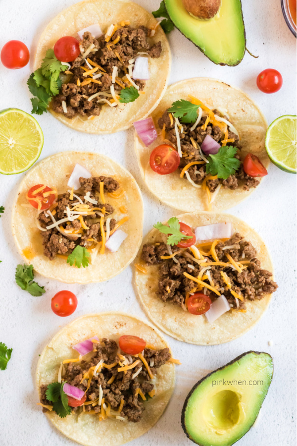 Ground Beef Street tacos with toppings and spread on a  white board. 