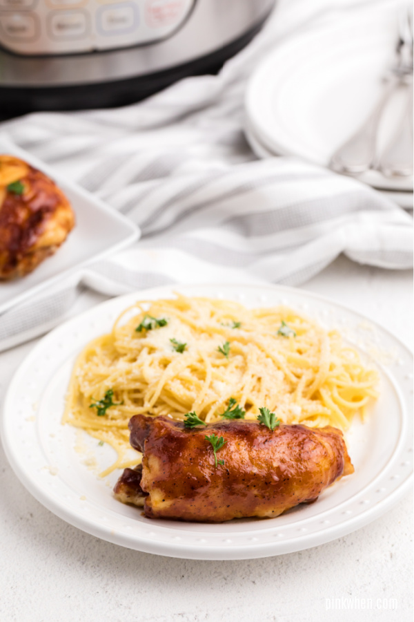 BBQ Chicken Thigh and butter garlic noodles on a white plate. 