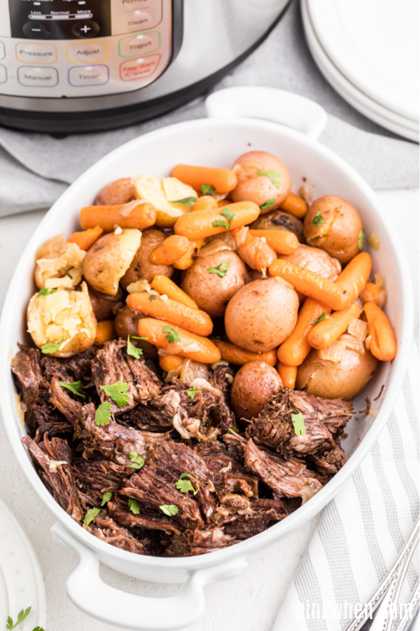 Instant Pot Pot Roast in a serving dish with vegetables. 
