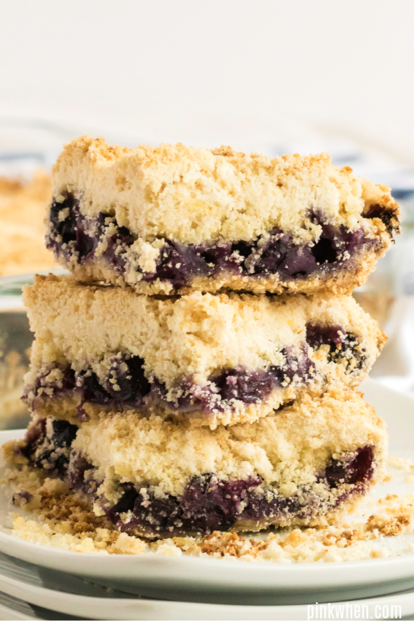 blueberry crumb bars cut and stacked on a plate.