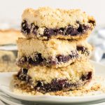 Blueberry crumb bars stacked on a plate and ready to eat.
