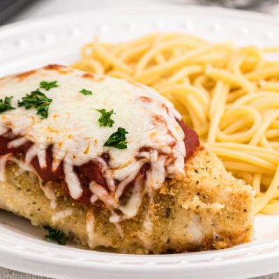 Oven baked chicken parmesan on a plate with noodles