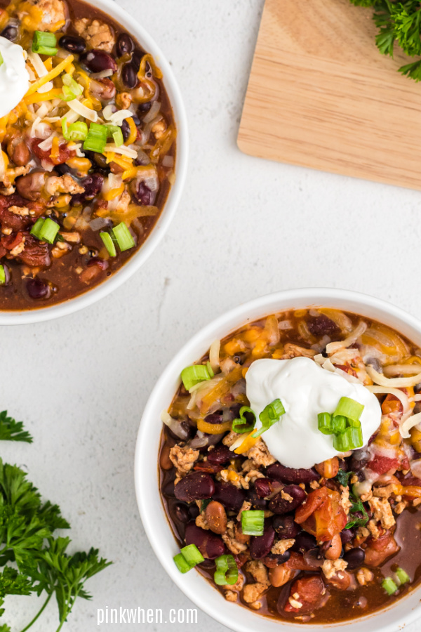 Slow Cooker Turkey Chili in a bowl topped with sour cream, cheese, and green onion tops. 