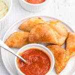 Homemade Air Fryer Pizza Rolls on a white plate with pizza dipping sauce.