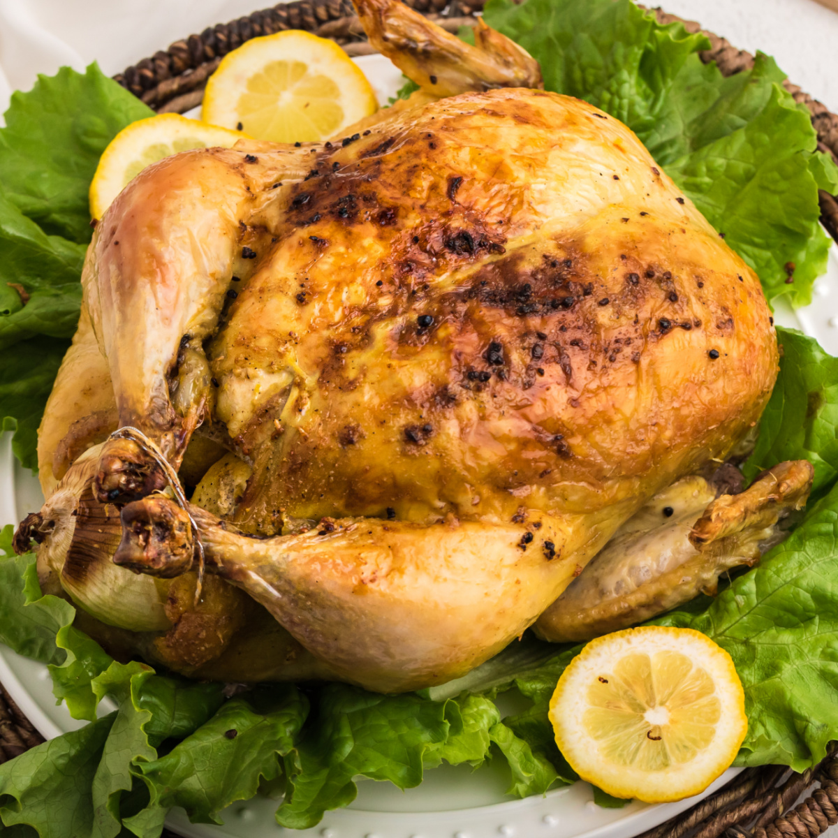 Slow Roasted Whole Chicken on a bed of lettuce with lemons.
