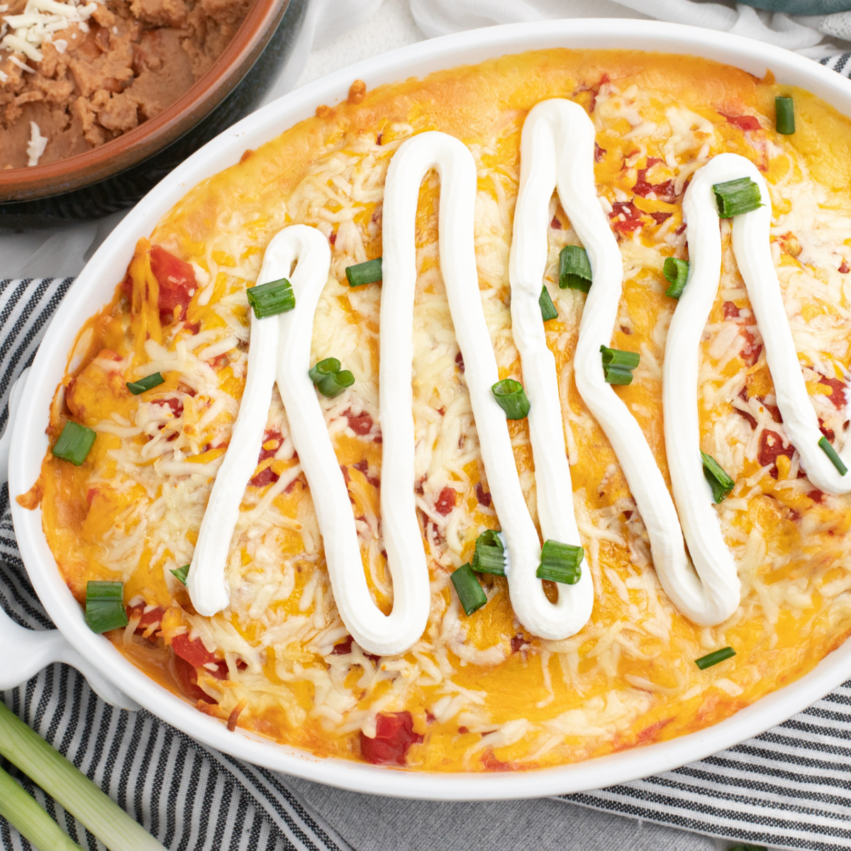 Taco casserole made with chicken covered with sour cream and green onion tops and ready to serve.