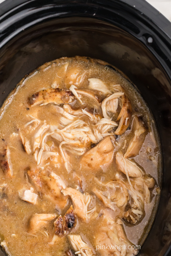 Cooked Chicken and gravy in the liner of a crockpot. 