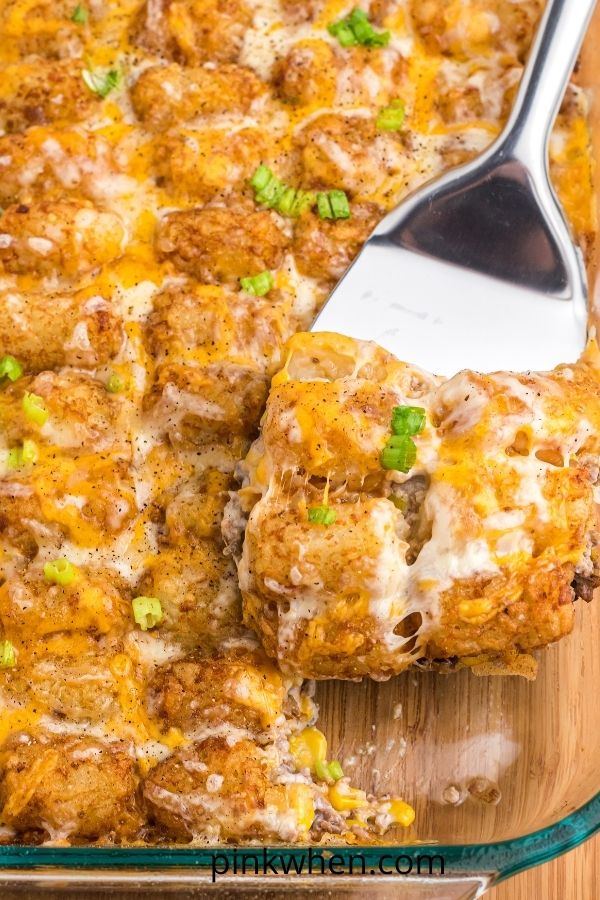 Cheesy Tater Tot casserole being scooped out of a baking dish. 