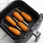 Corn dogs in a single layer in an Air Fryer basket.