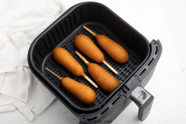 Corn dogs in a single layer in an Air Fryer basket.