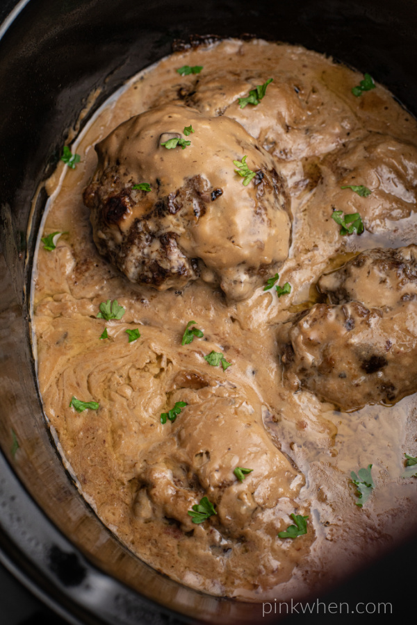 Black crock pot liner filled with gravy and Salisbury Steak. 