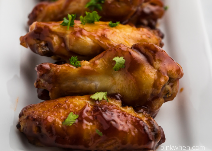 Air Fryer BBQ Chicken Wings on a white dish and topped with fresh parsley. 