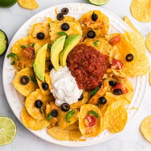 Air Fryer Nachos topped with sour cream, salsa, and avocado slices.