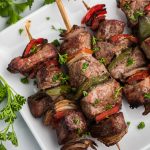 Steak Kabobs made in the Air Fryer and topped with fresh parsley. Served on a white plate.