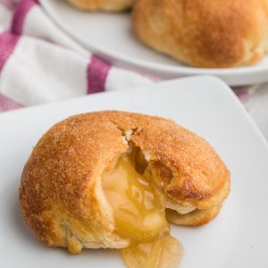 Apple Pie Bombs with a bite missing, on a white plate.