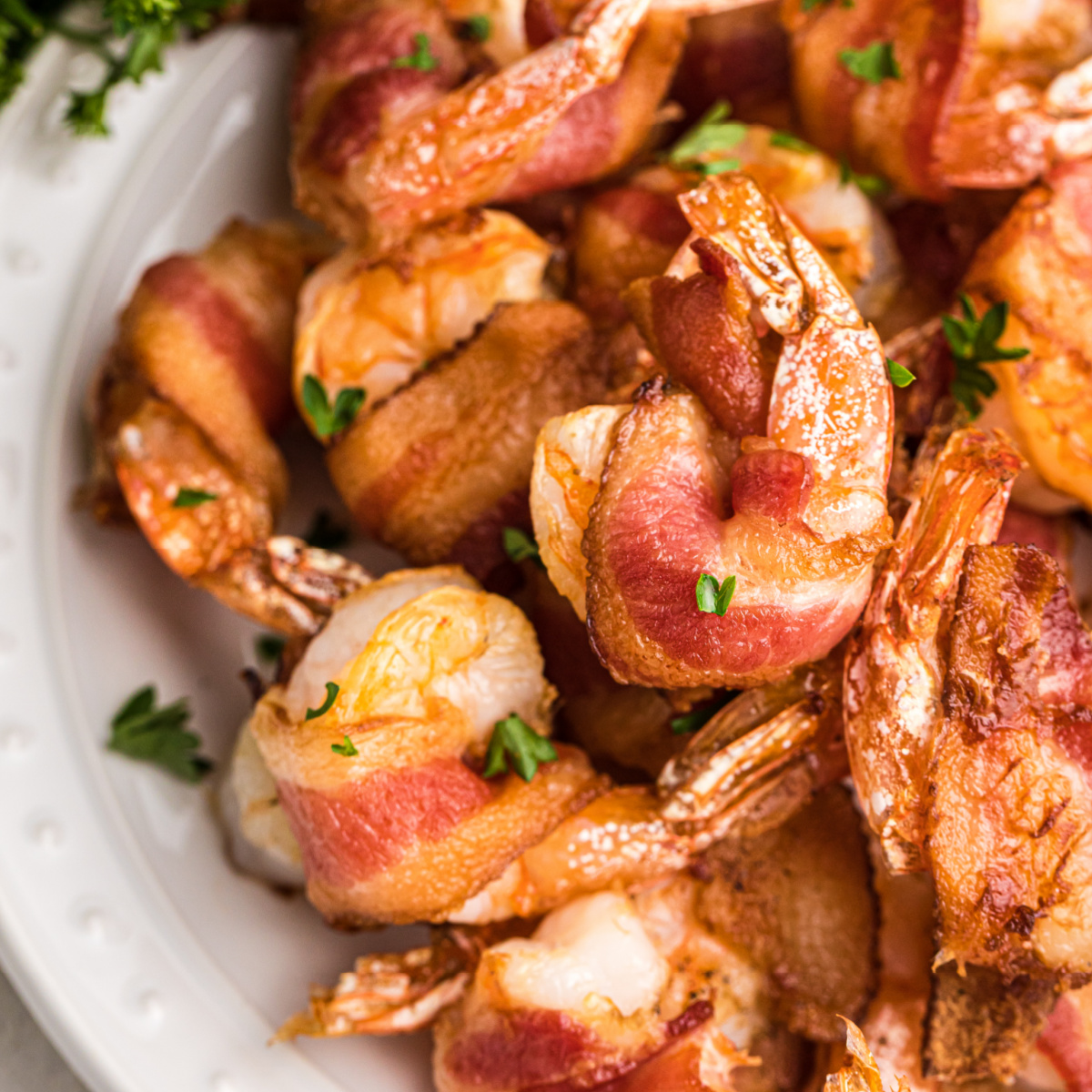 Bacon Wrapped Shrimp made in the air fryer on a white plate ready to serve.