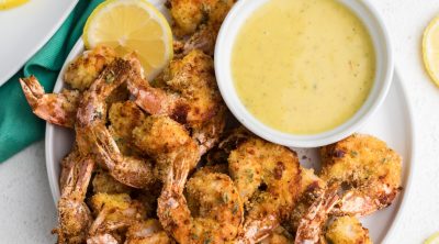 Air Fryer Fried Shrimp with lemon slices and serving sauce on a white plate.
