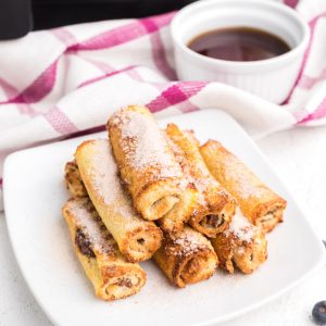 Nutella French Toast roll ups made in the air fryer and served on a white plate and topped with powdered sugar.