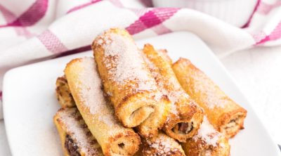 Nutella French Toast roll ups made in the air fryer and served on a white plate and topped with powdered sugar.