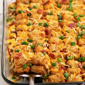 Bacon cheeseburger tater tot casserole being scooped from a casserole dish.