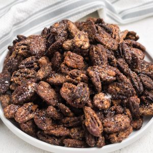Candied pecans made in the air fryer served on a white plate.