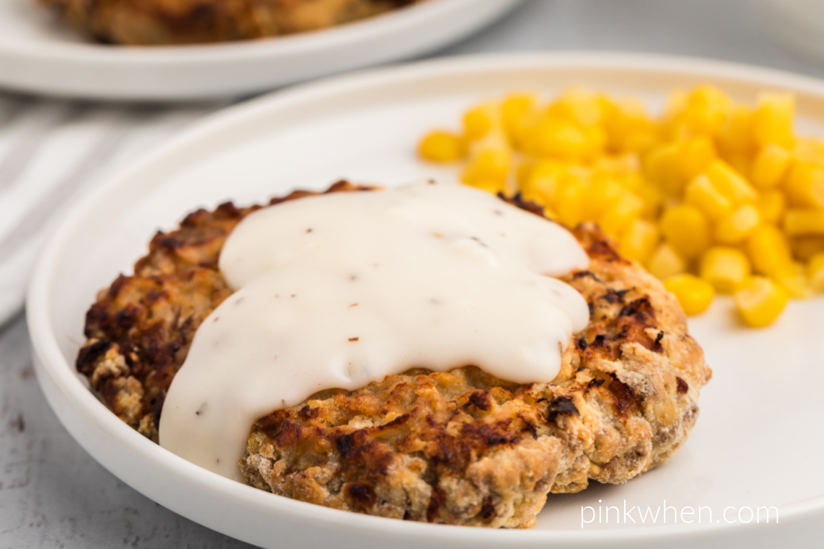Homemade air fryer chicken fried steak covered with white gravy on a plate. 
