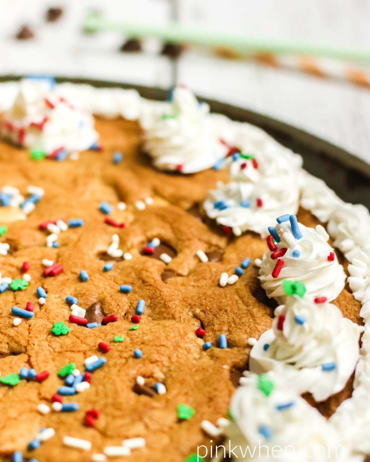 Cookie Cake with chocolate chips, frosting, and sprinkles on a white table. 