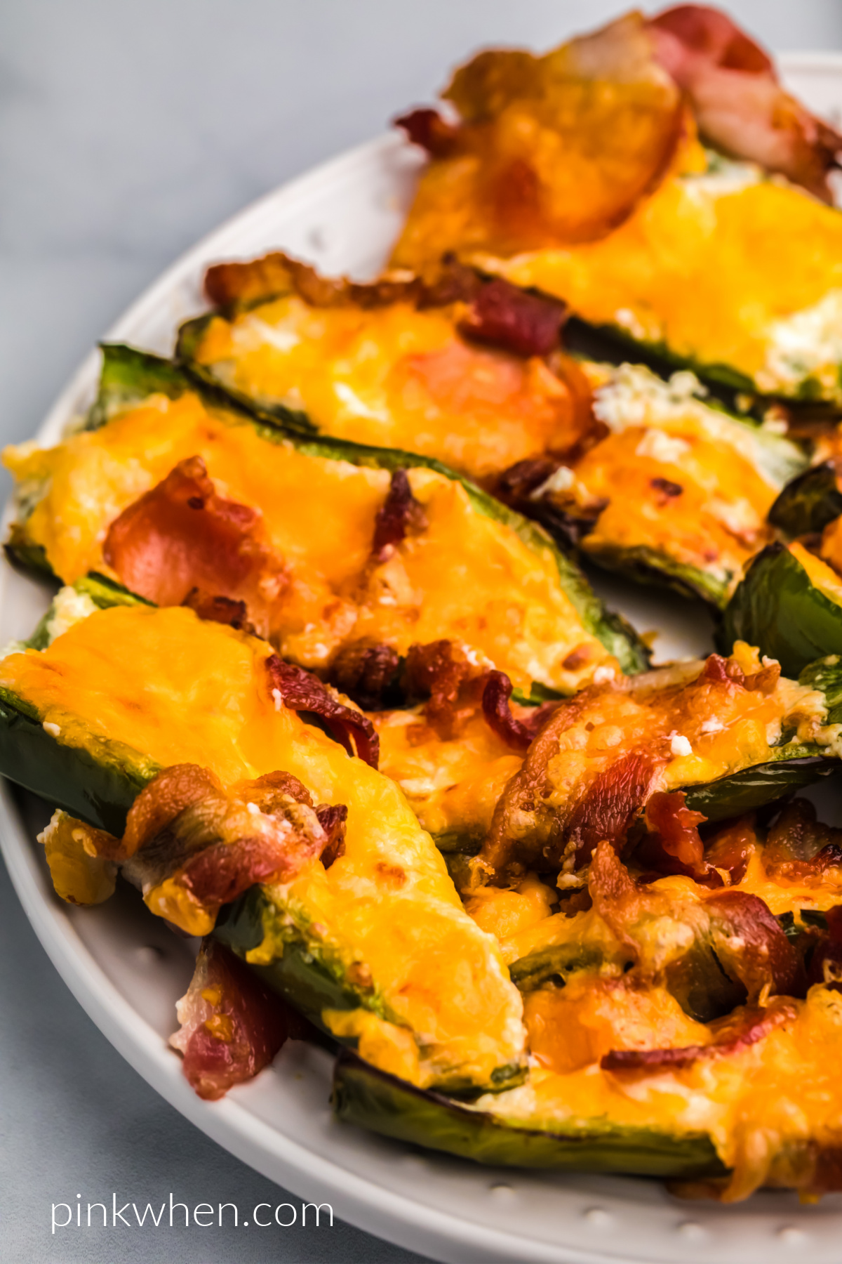 Bacon wrapped jalapenos on a white plate. 
