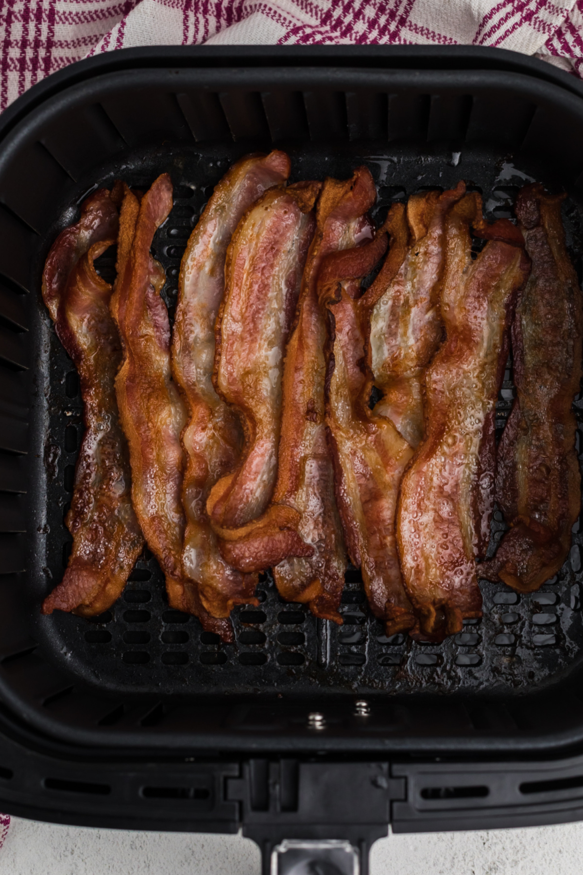 Cooked Crispy air fryer bacon in the basket of the air fryer. 