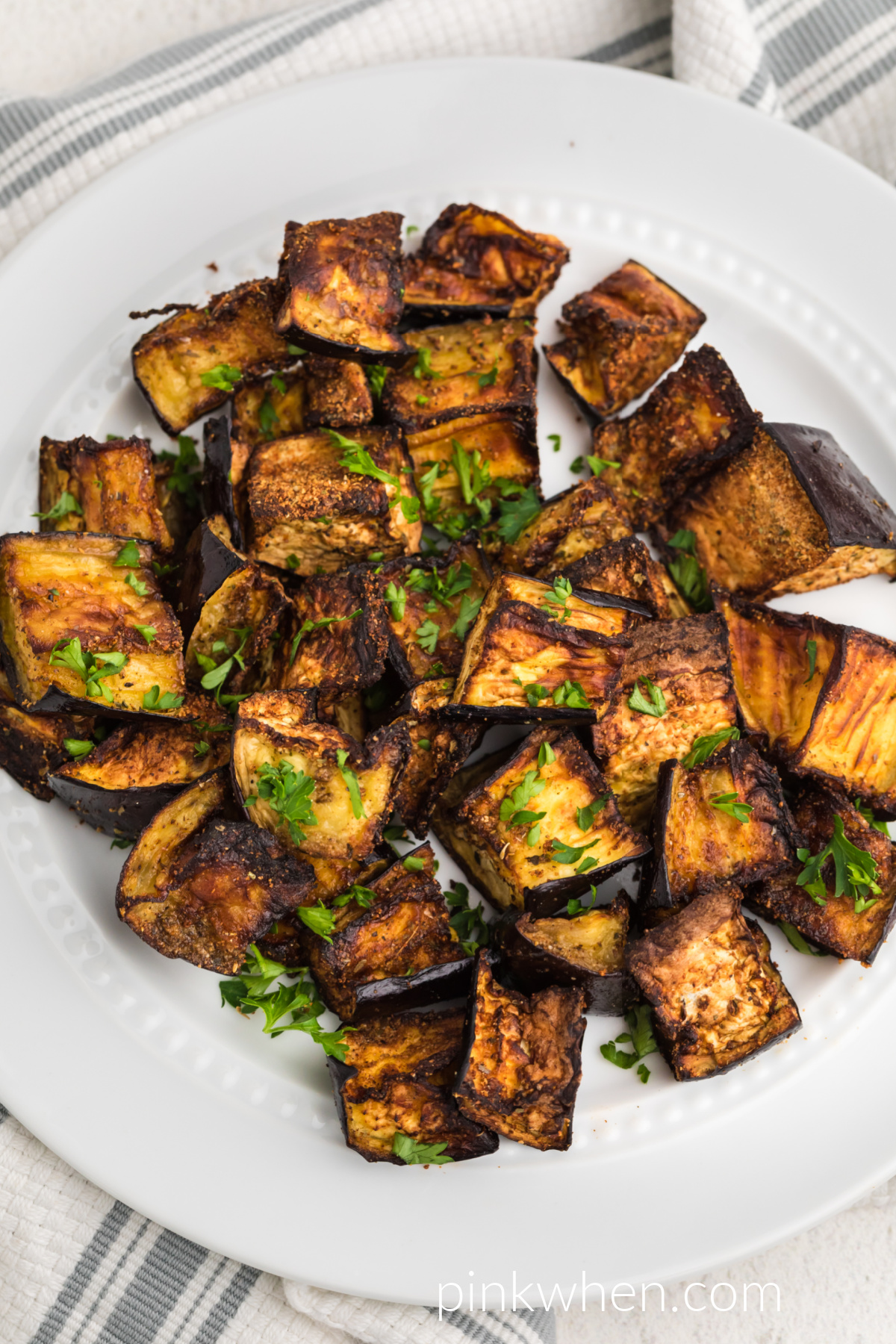 Crispy Air Fryer Eggplant seasoned with fresh parsley and served on a white plate. 