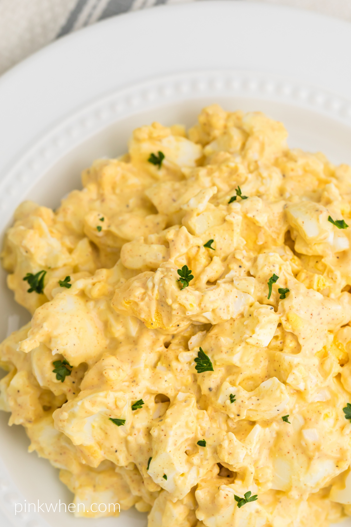 Classic egg salad in a white bowl ready to serve.