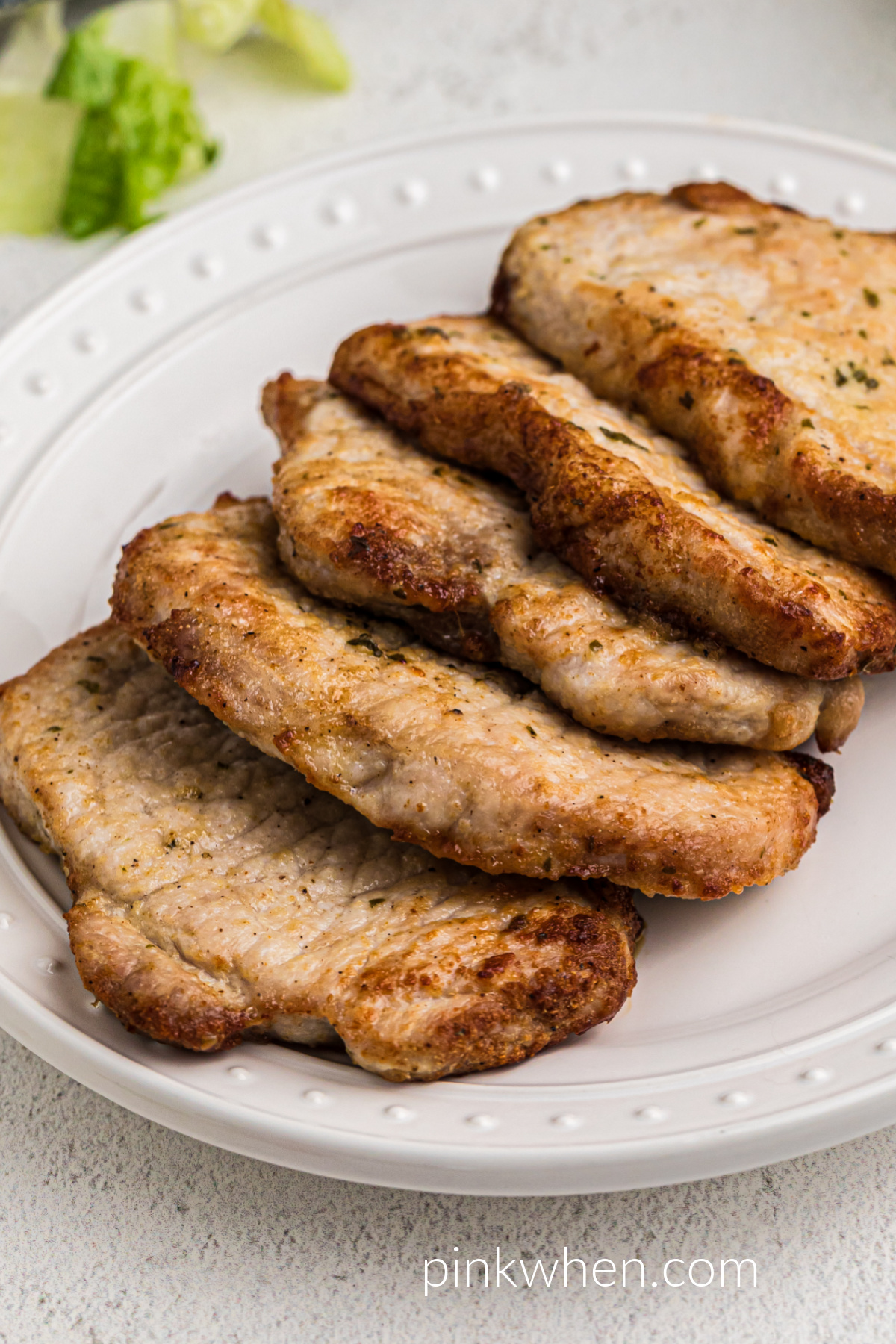 Cooked pork chops without breading on a white dish ready to serve.