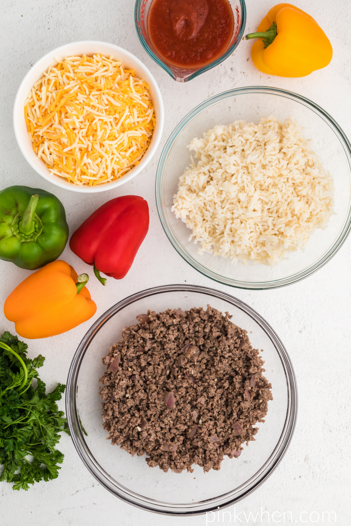 Ingredients needed to make stuffed bell peppers in the air fryer laid out on a white table. 