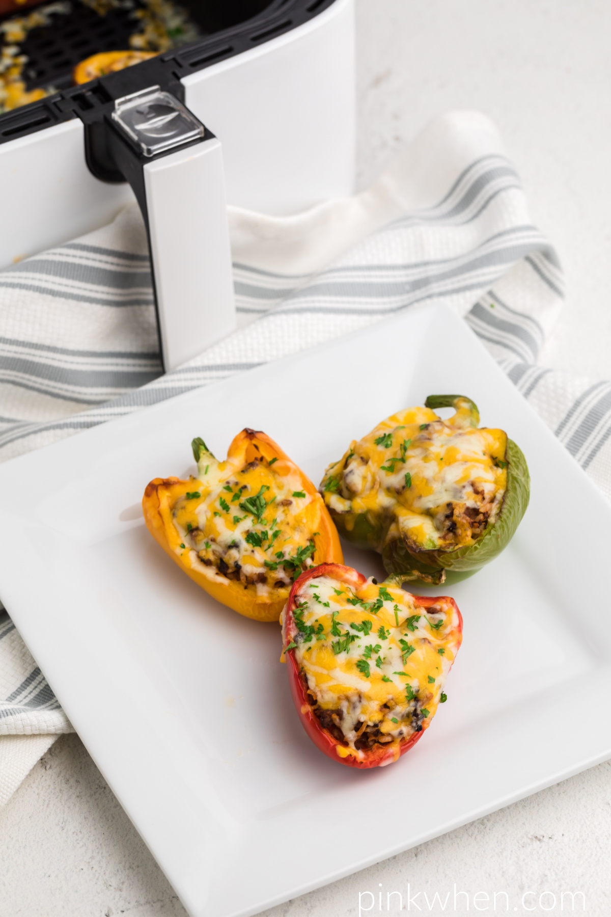Stuffed peppers on a white plate topped with cheese and fresh parsley 