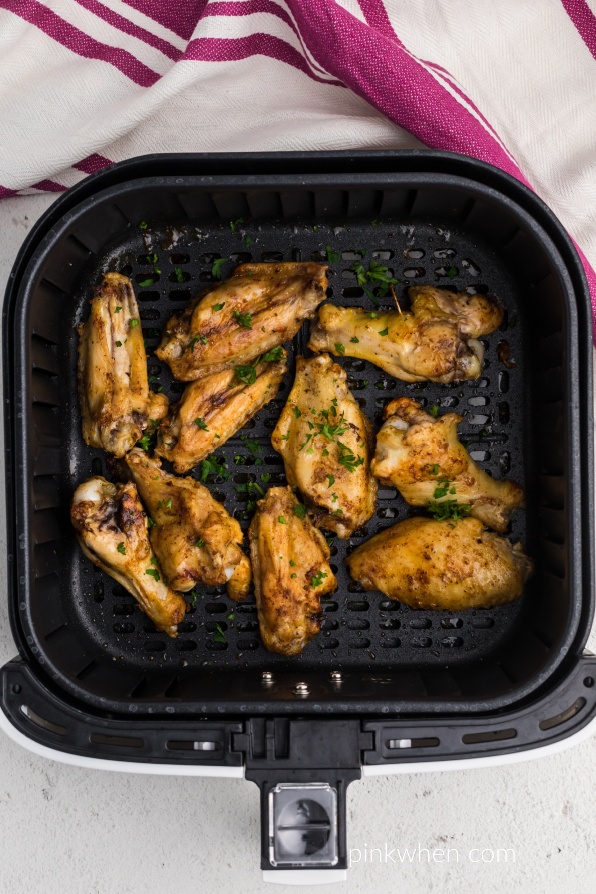 Seasoned chicken wings in the basket of the air fryer.