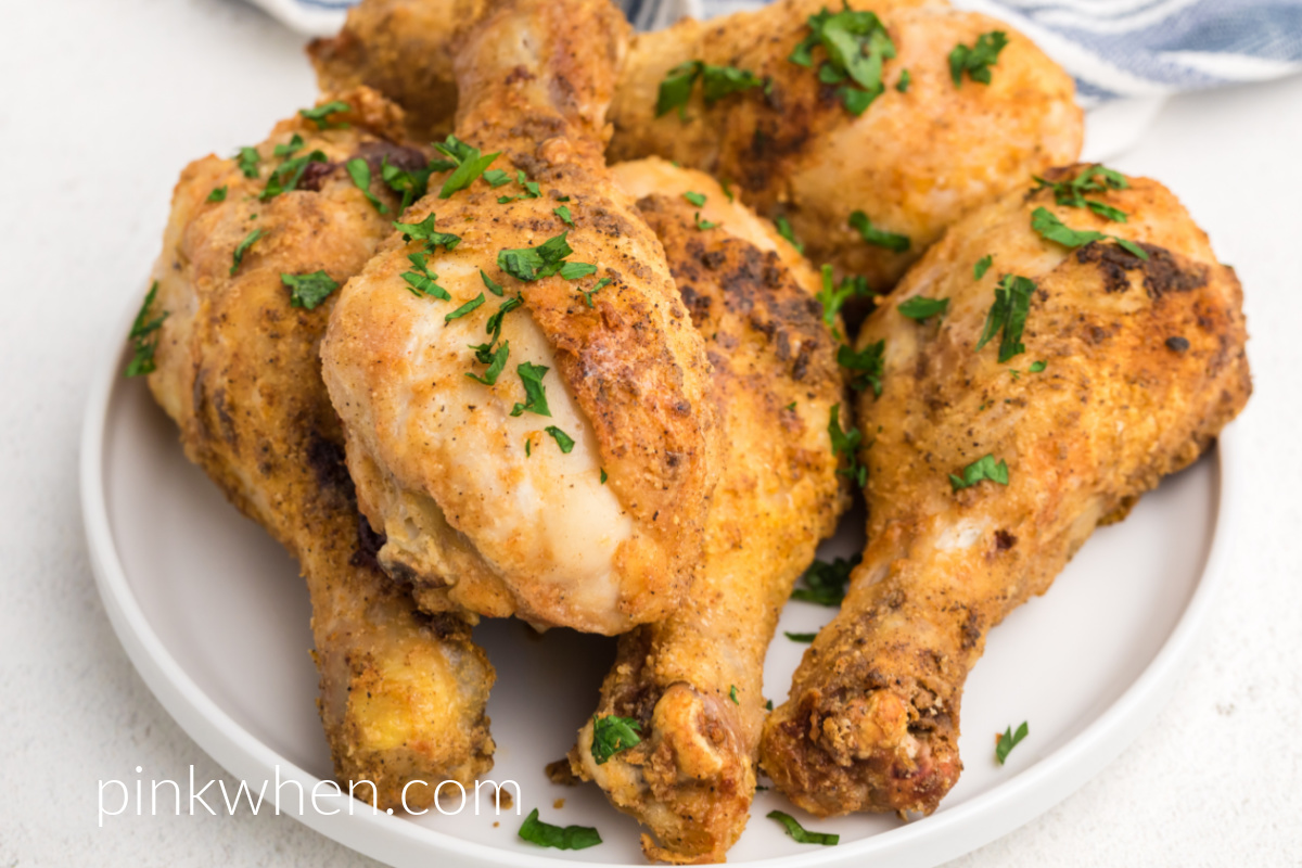 Seasoned and cooked air fryer chicken drumsticks on a white plate.