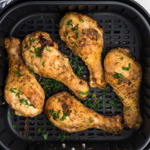 Overhead shot of cooked chicken drumsticks in a single layer in the air fryer basket.