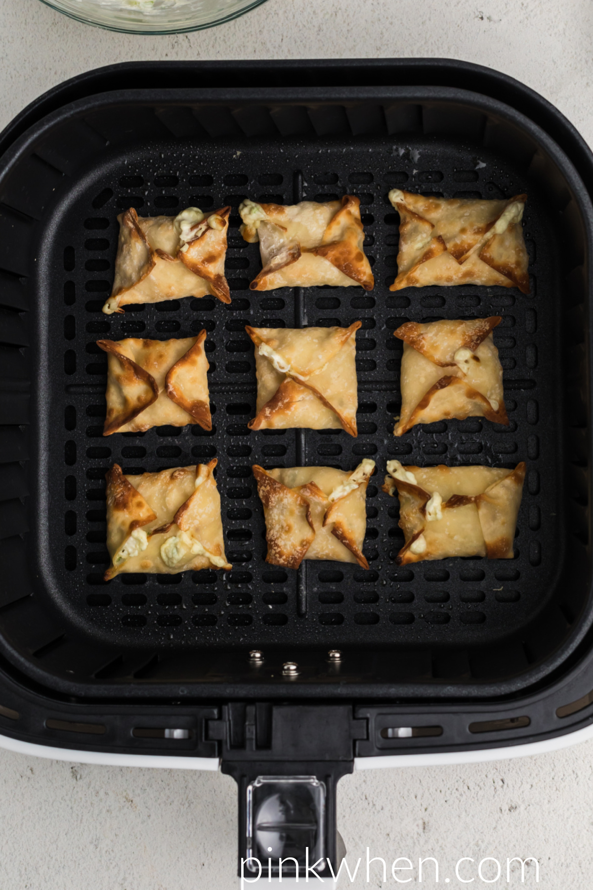 Air fried crab rangoon in the basket of the air fryer. 