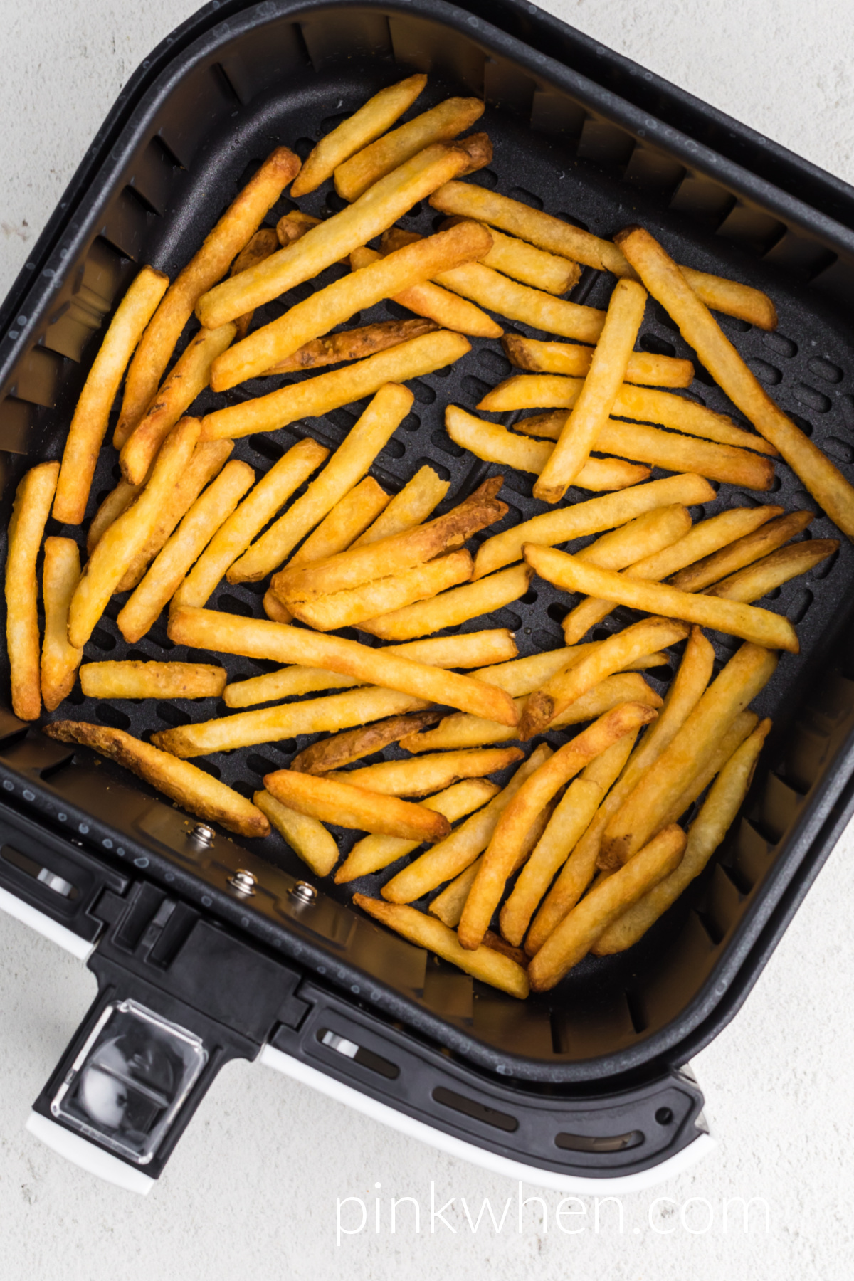 Fully cooked french fries in the basket of the air fryer.